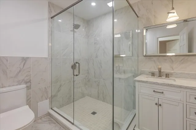 a bathroom with a shower sink mirror and toilet