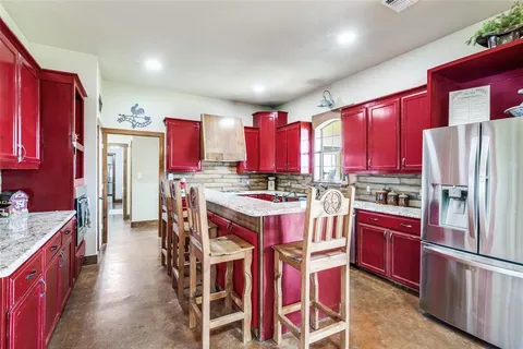 a kitchen with stainless steel appliances kitchen island granite countertop a refrigerator a stove a sink dishwasher and a refrigerator with wooden cabinets