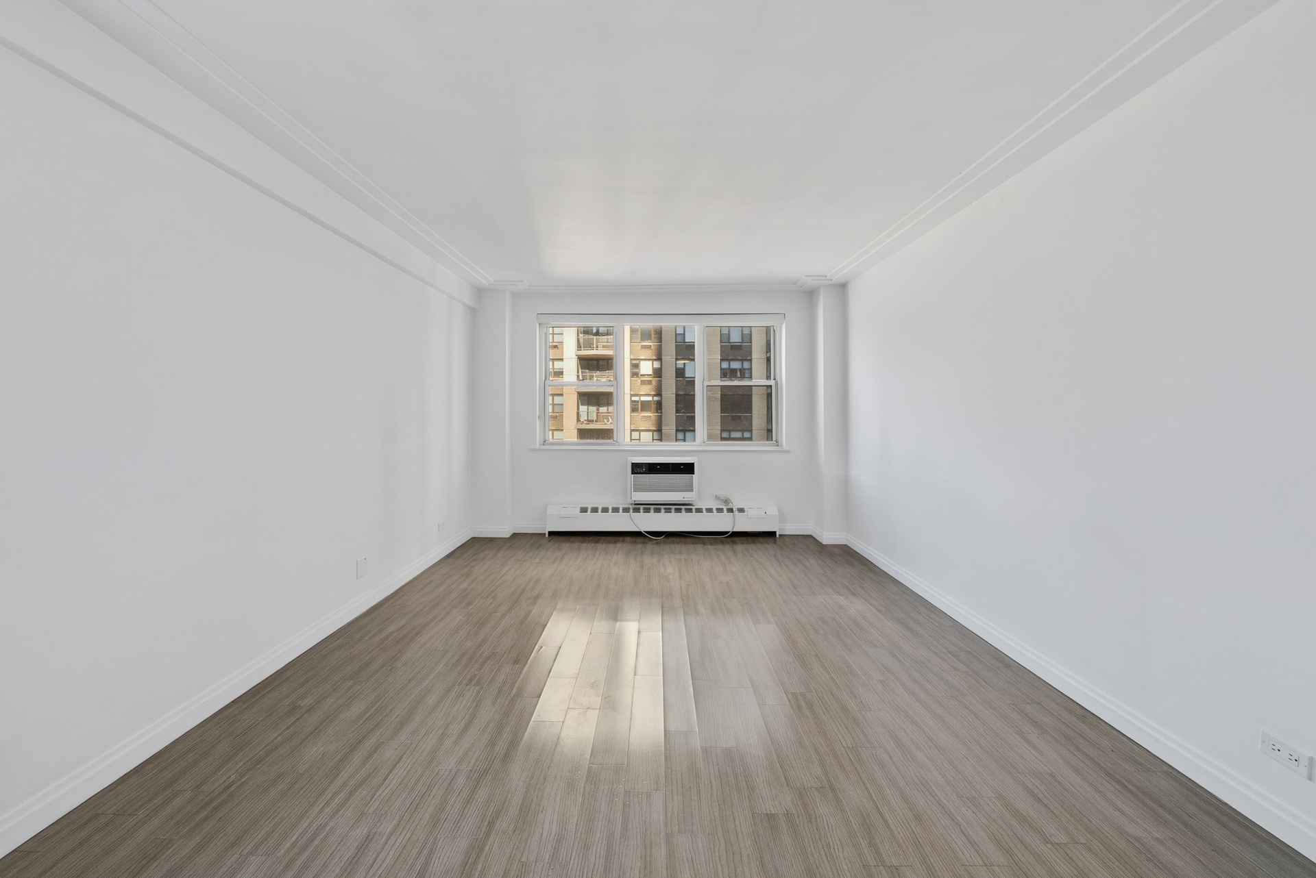 340 East 80th Street, Unit 17D Manhattan, NY 10075 - Photo 4 of 18 an empty room with wooden floor and windows
