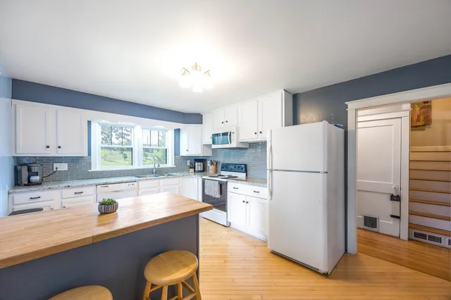 a kitchen with stainless steel appliances granite countertop a refrigerator a stove a microwave oven with a dining table and chairs