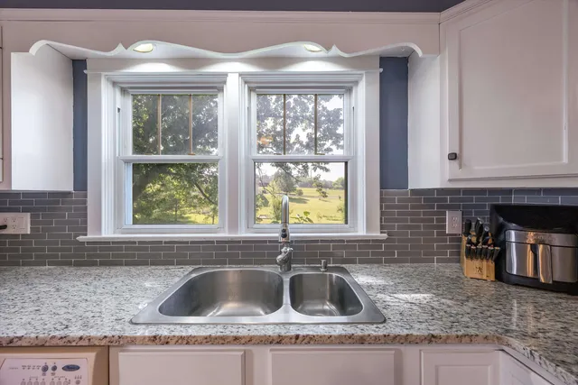 a kitchen with granite countertop a sink window and cabinets