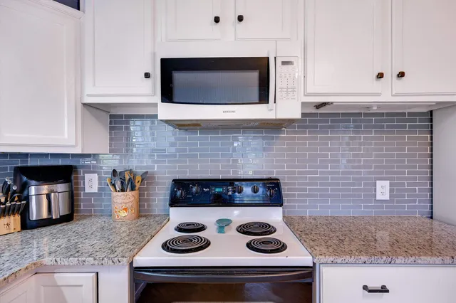 a kitchen with stainless steel appliances kitchen island granite countertop a stove a sink and white cabinets