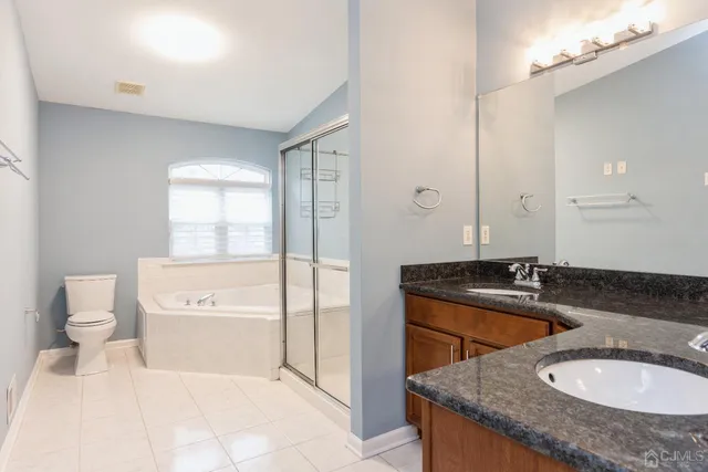 a bathroom with a granite countertop sink a toilet a mirror and bathtub