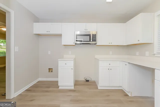a view of a kitchen with white cabinets and wooden floor
