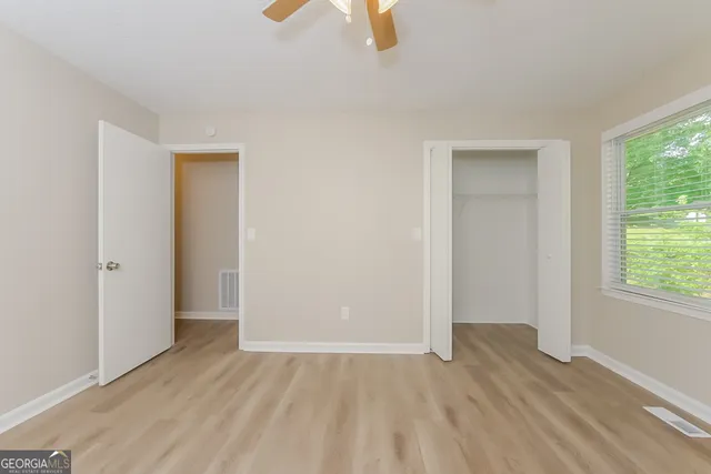 an empty room with wooden floor cabinet and windows
