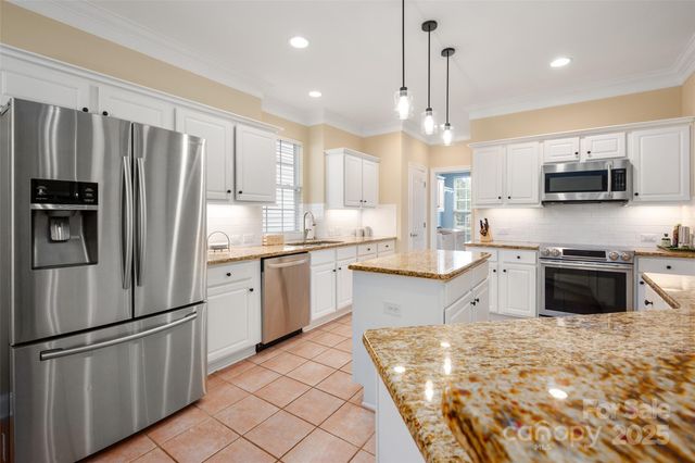 a kitchen with stainless steel appliances granite countertop a refrigerator a stove a sink and a microwave