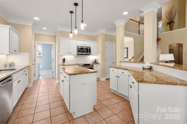 a large kitchen with granite countertop a sink a counter top space appliances and cabinets