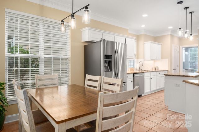 a kitchen with stainless steel appliances kitchen island granite countertop a table chairs in it and wooden floors
