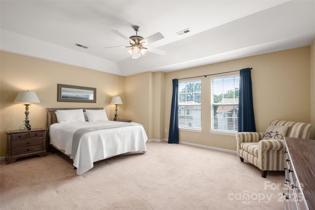 a spacious bedroom with a bed painting on wall and a large window