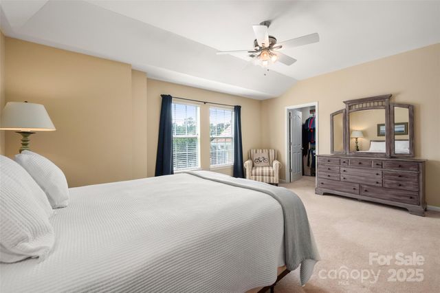 a spacious bedroom with a large bed a chandelier and windows