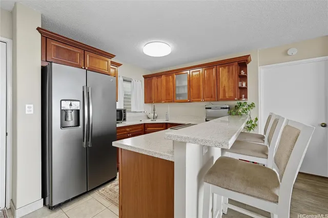 a kitchen with stainless steel appliances granite countertop a refrigerator a stove a sink a dining table and chairs with wooden floor