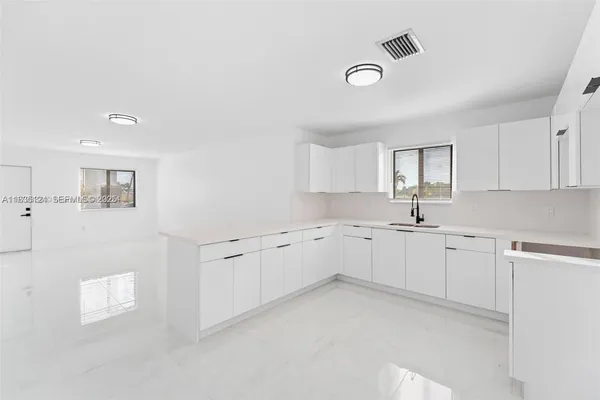a large white kitchen with cabinets