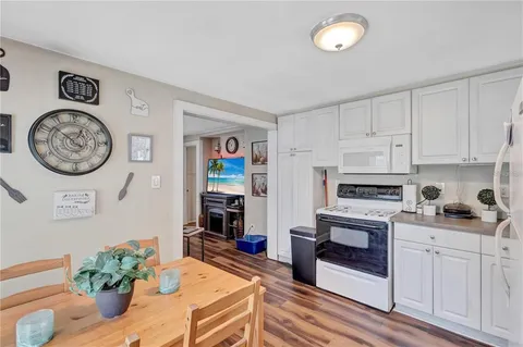 a living room with furniture a clock and a view of kitchen