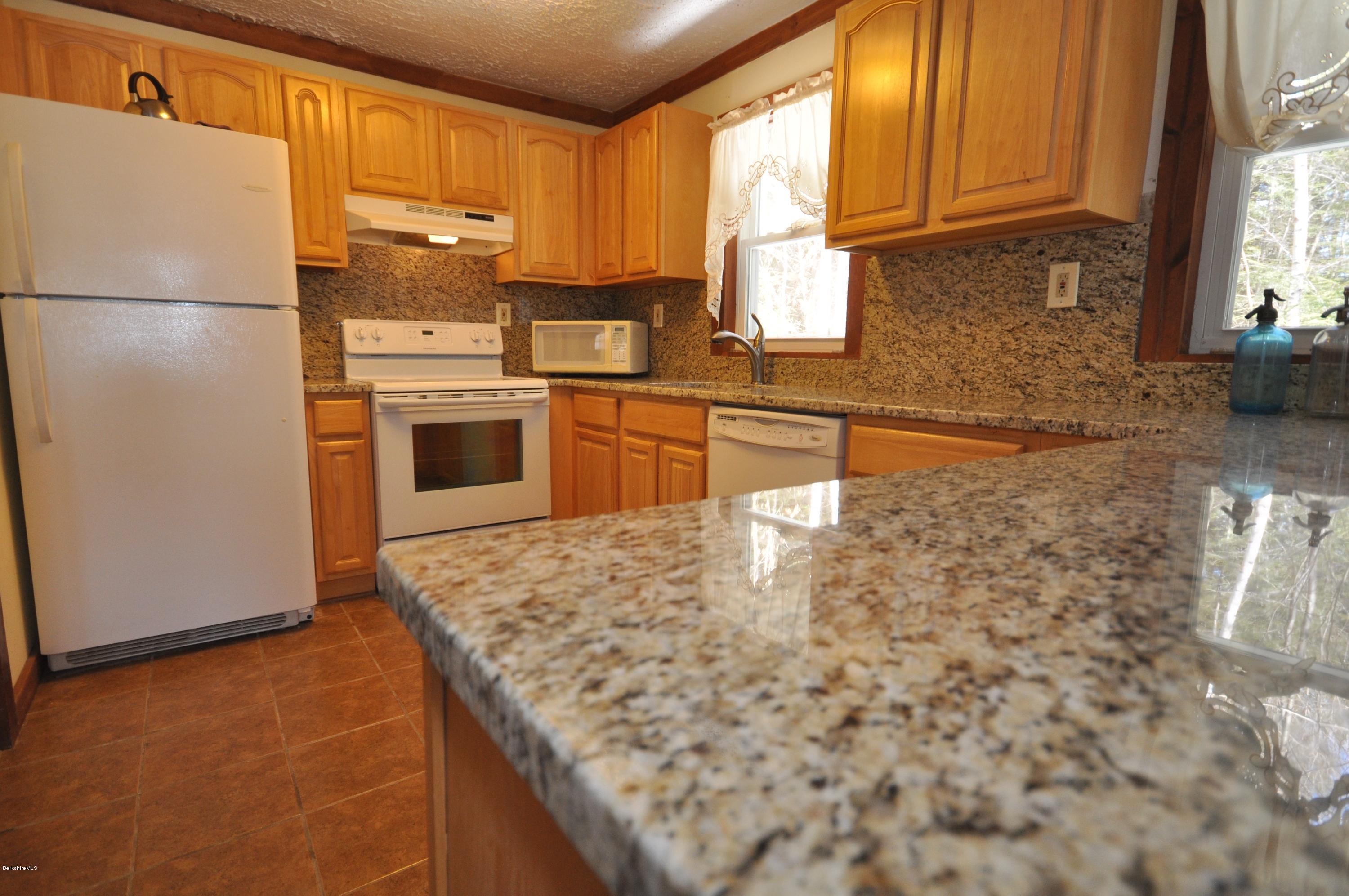 462 East Otis Road Tolland, MA 01034 - Photo 11 of 29 a kitchen with granite countertop a refrigerator a stove a sink and dishwasher