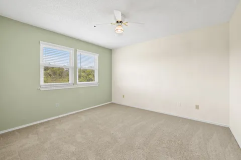 an empty room with a window and a ceiling fan