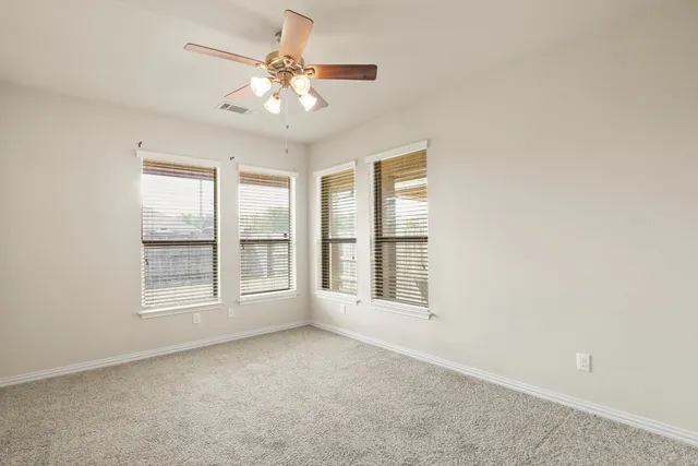 an empty room with chandelier fan and windows