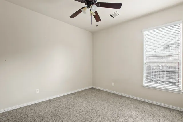 an empty room with a window and a fan