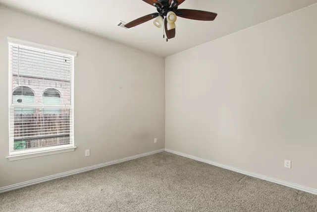 an empty room with a window and a fan