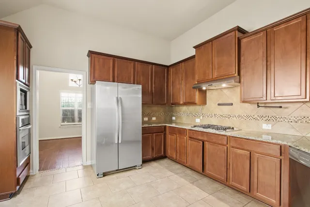 a kitchen with stainless steel appliances granite countertop a refrigerator and a sink
