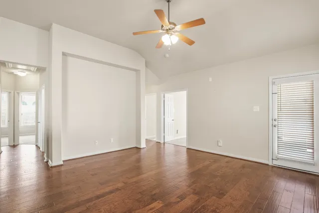 an empty room with wooden floor and a ceiling fan