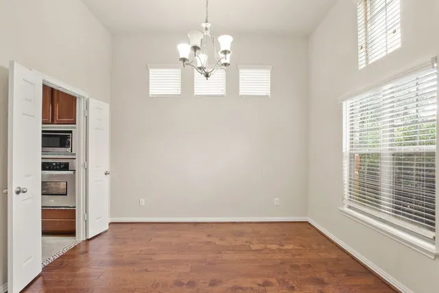 a view of an empty room with a window and kitchen view