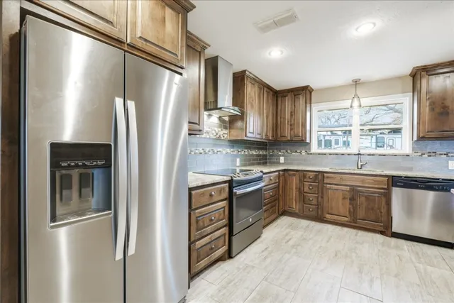 a kitchen with stainless steel appliances granite countertop a refrigerator and a stove top oven