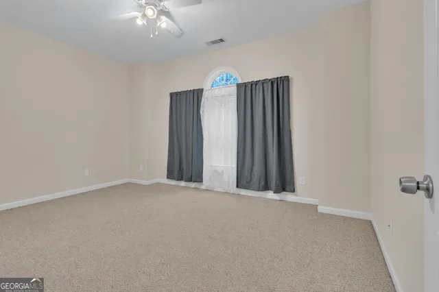 an empty room with a ceiling fan and a window