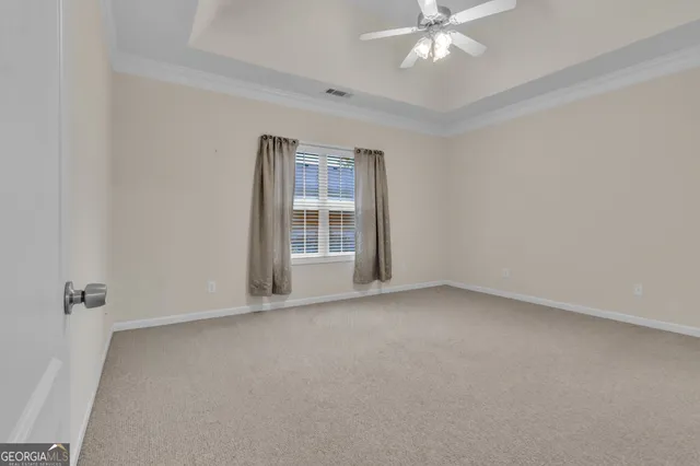 an empty room with chandelier fan and windows