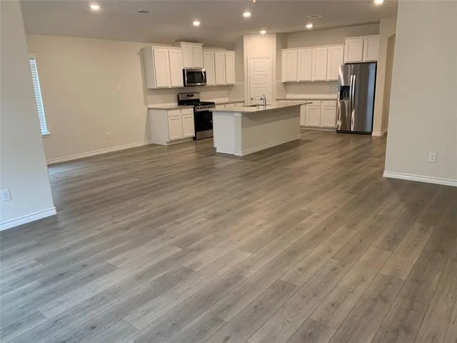a large kitchen with cabinets wooden floor and a stainless steel appliances