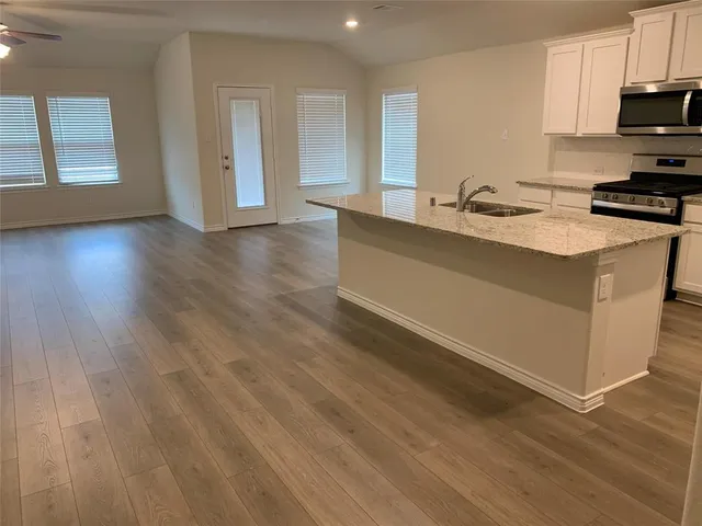 a kitchen with stainless steel appliances granite countertop a sink a stove and a wooden floors