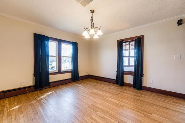 a view of an empty room with window and wooden floor
