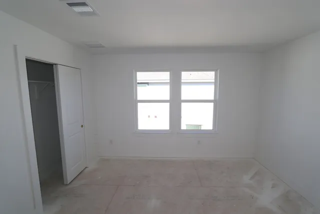 an empty room with windows and fan