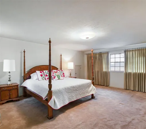 a bedroom with a bed a large window and potted plants