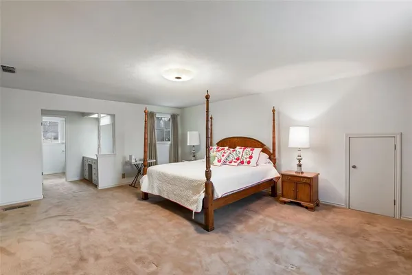 a spacious bedroom with a bed and dresser