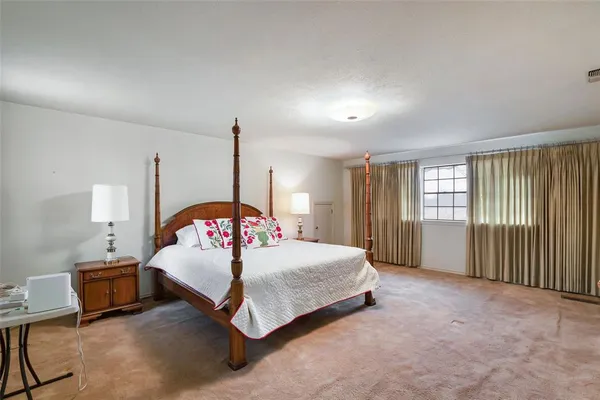 a spacious bedroom with a bed table and a window
