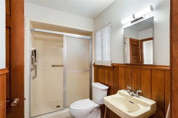 a bathroom with a sink a toilet a mirror and shower