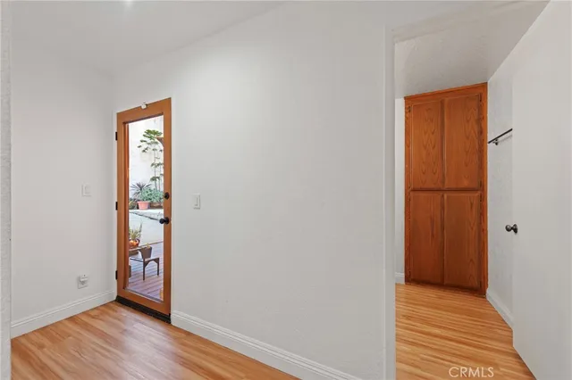 an empty room with wooden floor mirror and entrance