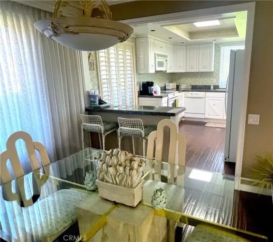 a kitchen with stainless steel appliances granite countertop a sink a stove a dining table and chairs with wooden floor