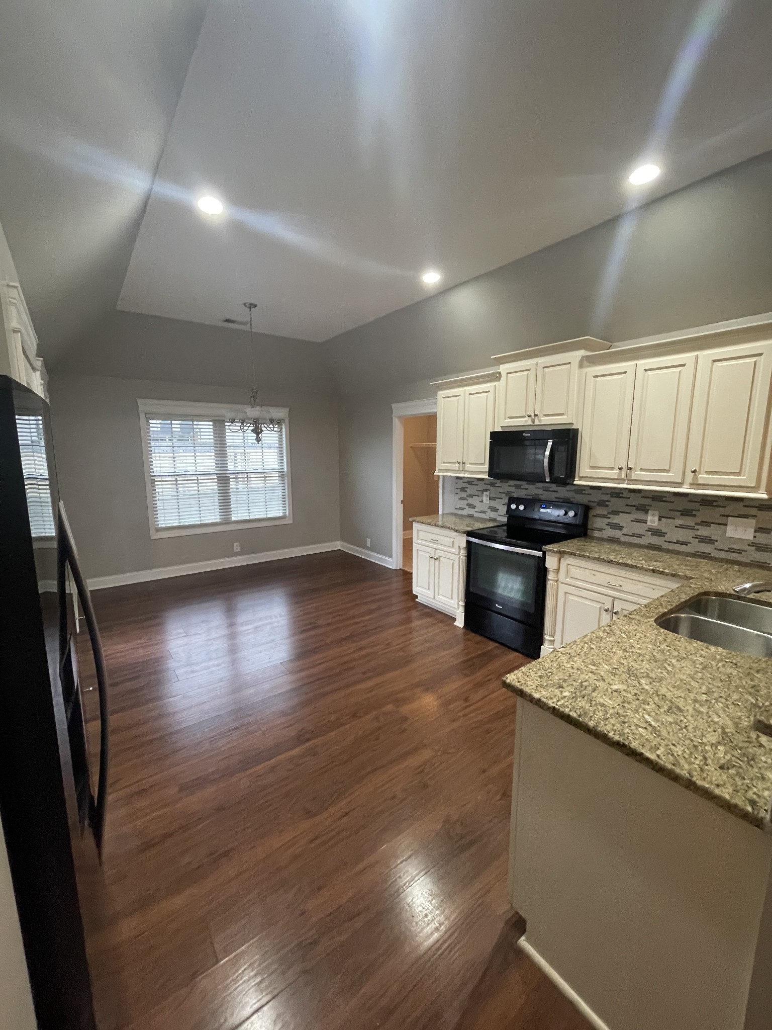 4815 Conquer Drive Murfreesboro, TN 37128 - Photo 4 of 10 a kitchen with stainless steel appliances granite countertop a sink a stove a microwave a refrigerator a sink and dishwasher with wooden floor