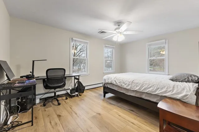 a bedroom with a bed a desk and chair with wooden floor