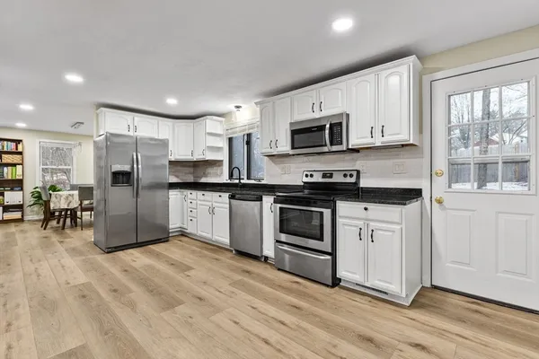 a kitchen with granite countertop a refrigerator and a stove top oven