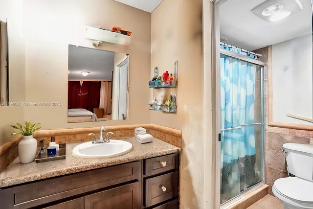 a bathroom with a granite countertop sink toilet and shower