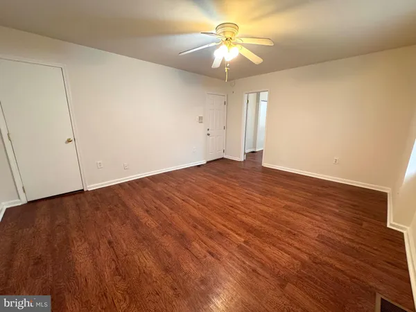 an empty room with wooden floor and chandelier fan