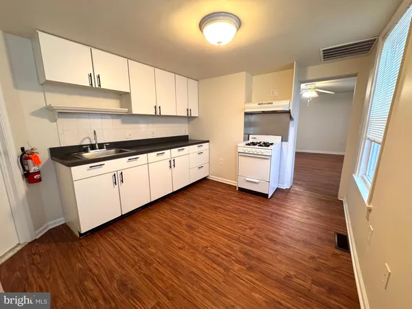 a kitchen with granite countertop wooden floors and white stainless steel appliances