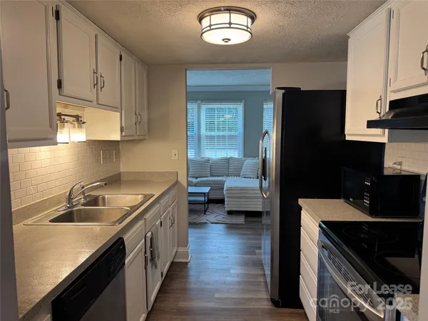 a kitchen with a sink dishwasher a stove and a refrigerator with wooden floor