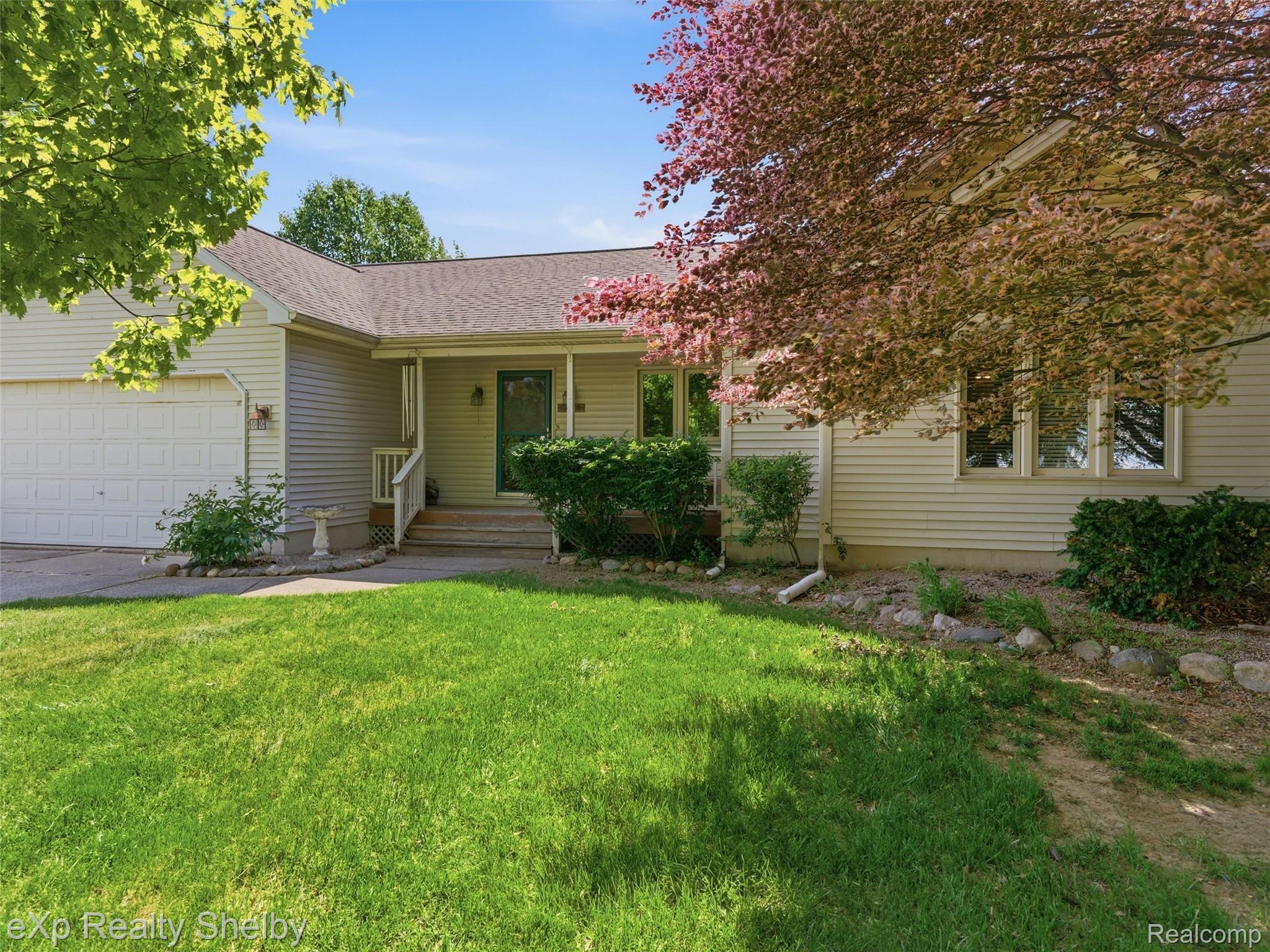 4154 Union Street Dryden, MI 48428 - Photo 2 of 41 Residential exterior featuring light-colored siding, an attached garage, a covered front entry with a dark-colored door, and mature trees providing natural shading