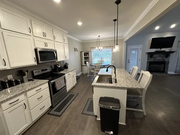 a kitchen with granite countertop a stove a sink and a microwave