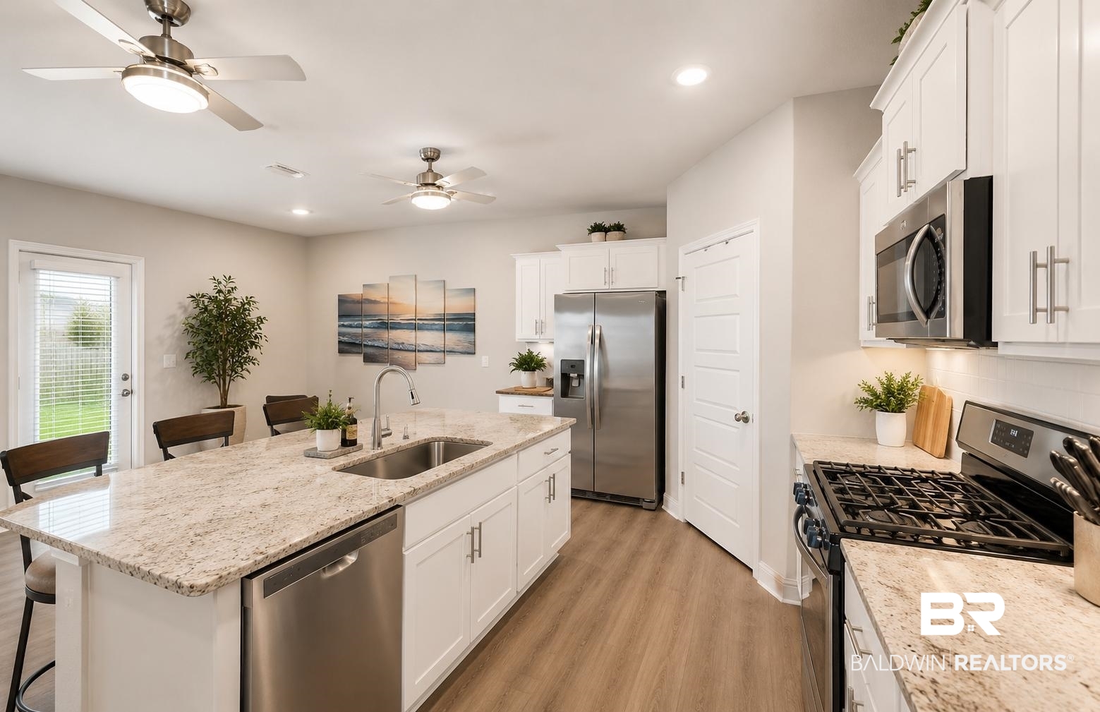 31468 Memphis Loop Daphne, AL 36527 - Photo 5 of 24 Kitchen featuring an expansive island with a stainless steel sink and dishwasher, light-toned granite countertops, white cabinetry with brushed nickel hardware, and stainless steel appliances including a refrigerator, microwave, and gas range