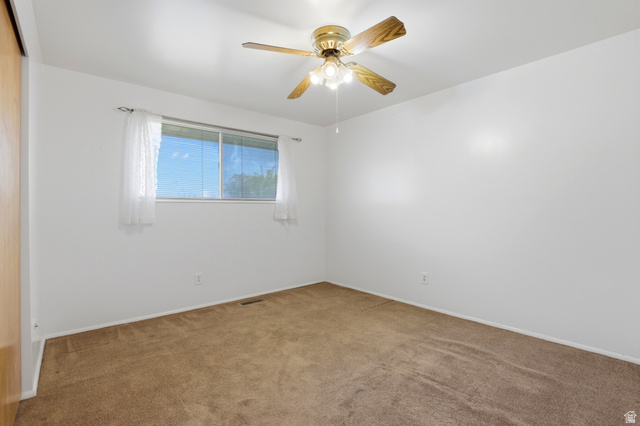 2348 North 770 West Clinton, UT 84015 - Photo 10 of 25 Room with white walls and brown carpet flooring, featuring a window, built-in ceiling fan with light fixture, and a sliding closet door