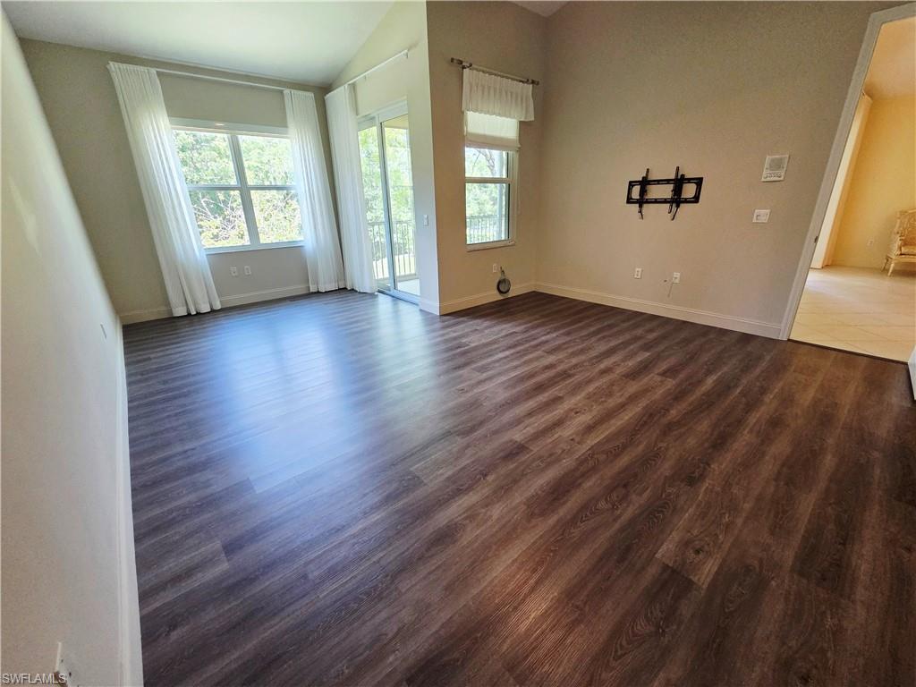 6775 Huntington Lakes Circle, Unit 202 Naples, FL 34119 - Photo 7 of 46 an empty room with wooden floor and windows
